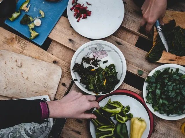 Jardinier utilisant une tablette pour analyser ses notes de récolte devant un carré potager en bois rempli de légumes.